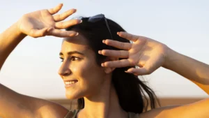 Smiling woman shielding her eyes from the sun outdoors